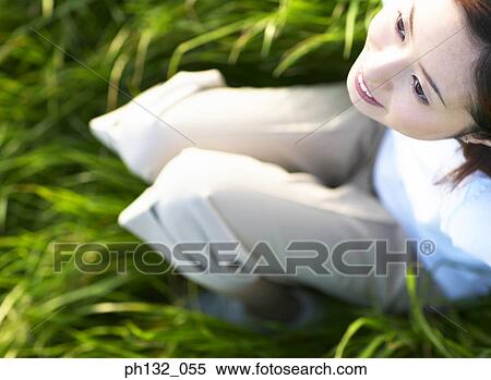 Stock Photography - Young woman sitting on grass. Fotosearch