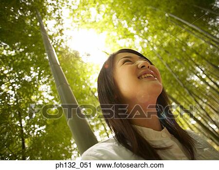 Young woman smiling in a bamboo plantation View Large Photo Image Stock Image - Young woman smiling in a bamboo plantation. Fotosearch