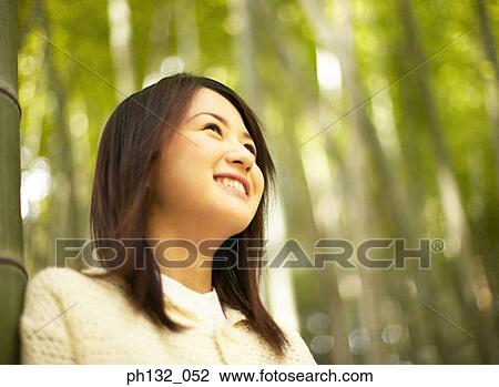 Young woman smiling in a forest View Large Photo Image Stock Image - Young woman smiling in a forest. Fotosearch