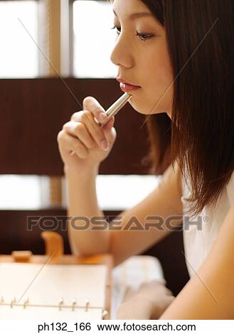 Stock Photograph - Young girl holding pen and thinking. Fotosearch
