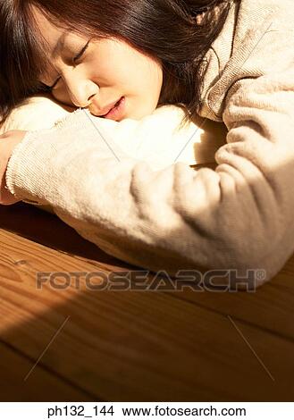 Picture - Young woman asleep on the floor. Fotosearch