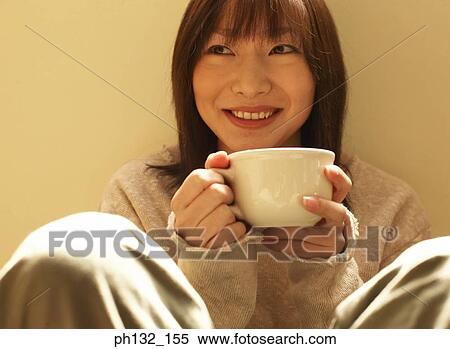 Young woman enjoying a cup of tea View Large Photo Image Stock Photography - Young woman enjoying a cup of tea. Fotosearch