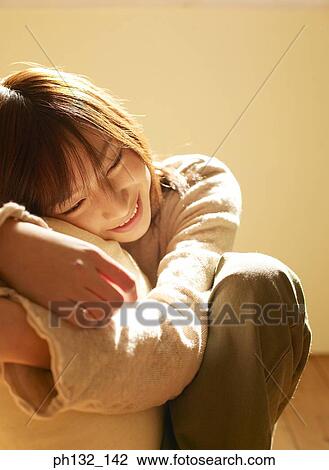 Stock Image - Young woman leaning on pillow. Fotosearch