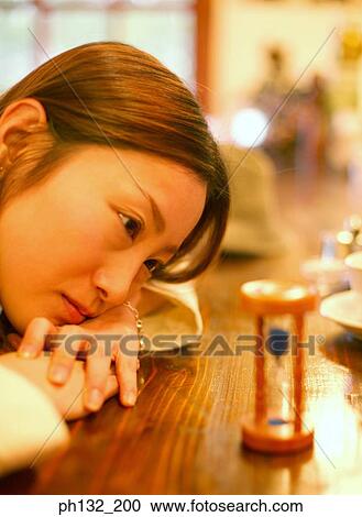 Young woman looking at an hourglass View Large Photo Image Stock Image - Young woman looking at an hourglass. Fotosearch