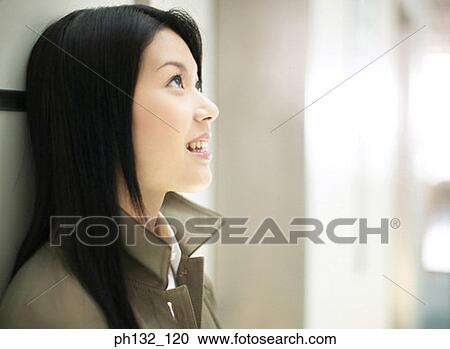 Stock Image - Young woman looking up and smiling. Fotosearch