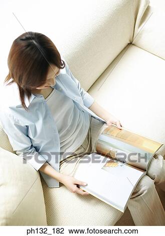 Young woman reading a magazine View Large Photo Image Stock Image - Young woman reading a magazine. Fotosearch
