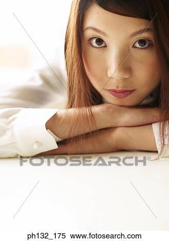 Stock Photography - Young woman resting her face on her arms. Fotosearch