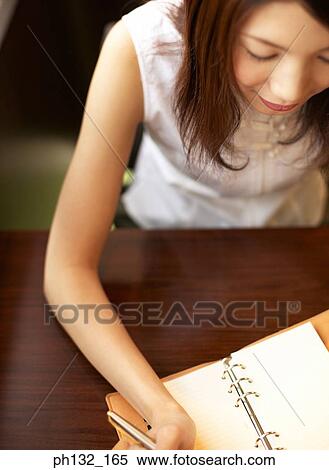 Young woman writing in a diary View Large Photo Image Stock Photography - Young woman writing in a diary. Fotosearch