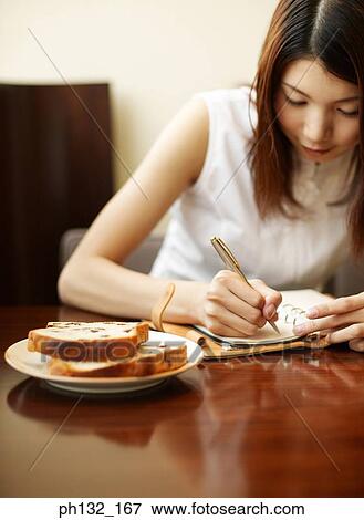Stock Photo - Young woman writing on note book. Fotosearch