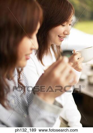 Young women enjoying a cup of tea View Large Photo Image Stock Photo - Young women enjoying a cup of tea. Fotosearch