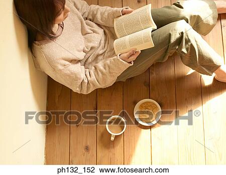 Stock Image - Young women reading book with refreshments. Fotosearch