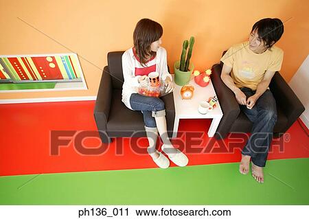 High angle view of a young couple sitting on a couch View Large Photo Image Stock Image - High angle view of a young couple sitting on a couch. Fotosearch