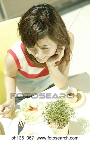 High angle view of a young woman seated at a table View Large Photo Image Stock Photo - High angle view of a young woman seated at a table. Fotosearch