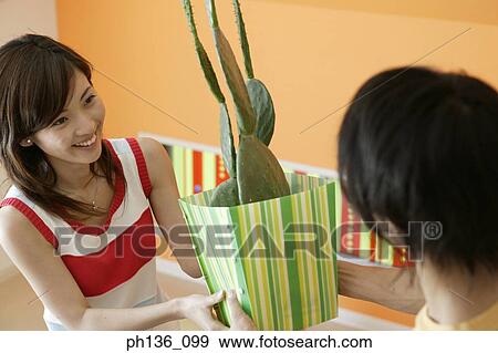 Stock Photo - Young coupe holding a potted cactus plant. Fotosearch