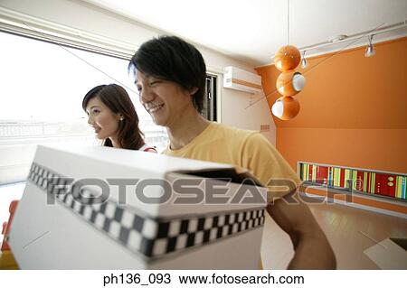 Stock Image - Young couple carrying boxes. Fotosearch