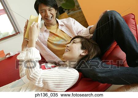 Stock Photography - Young couple on a couch reading a book. Fotosearch