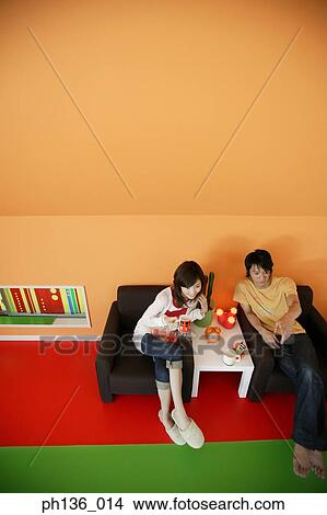 Young couple sitting on a couch View Large Photo Image Picture - Young couple sitting on a couch. Fotosearch