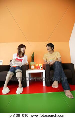 Stock Image - Young couple sitting on a couch. Fotosearch
