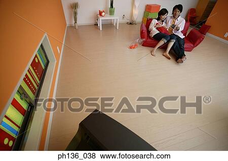 Stock Photo - Young couple sitting on a couch. Fotosearch