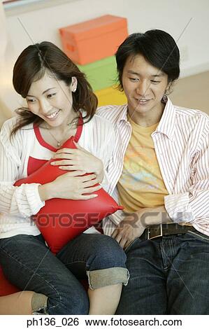 Stock Photograph - Young couple sitting together on a couch. Fotosearch