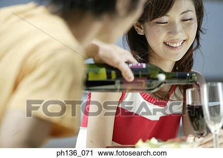 Young man pouring red wine into a woman's glass View Large Photo Image Stock Image - Young man pouring red wine into a woman's glass. Fotosearch