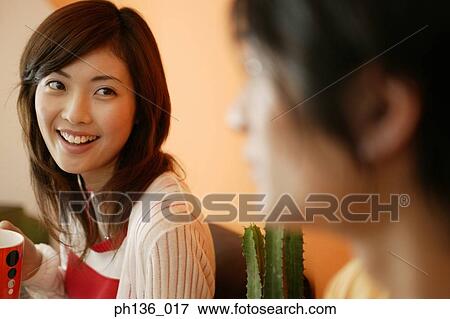 Stock Photo - Young woman holding a coffee cup looking at a man. Fotosearch