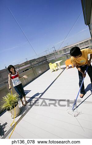 Young woman holding a hose while a man mops the floor View Large Photo Image Stock Photo - Young woman holding a hose while a man mops the floor. Fotosearch