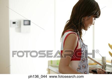 Picture - Young woman working in the kitchen. Fotosearch