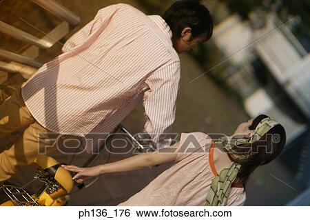 Rear view of a young couple walking holding a bicycle View Large Photo Image Stock Photograph - Rear view of a young couple walking holding a bicycle. Fotosearch