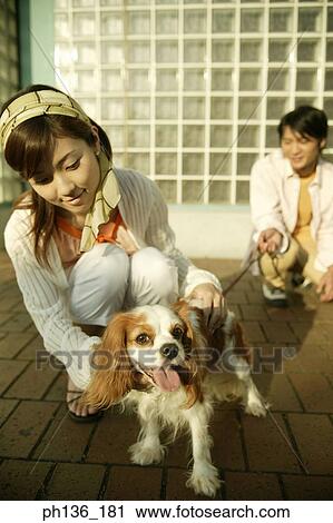 Stock Image - Young couple holding a dog. Fotosearch