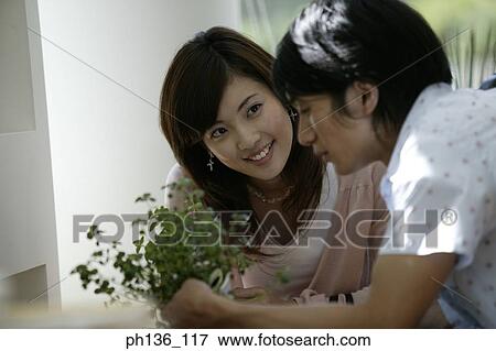 Young couple holding a potted plant View Large Photo Image Stock Photo - Young couple holding a potted plant. Fotosearch