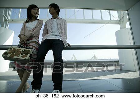 Stock Image - Young couple Leaning back against a railing. Fotosearch