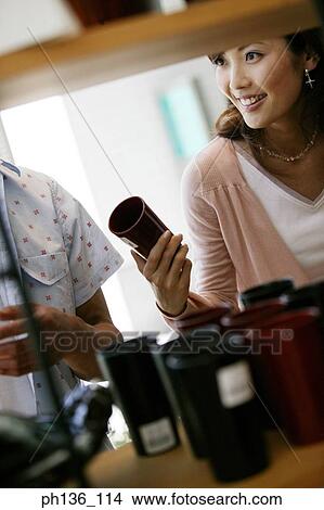 Picture - Young couple looking at items for sale on a shelf. Fotosearch