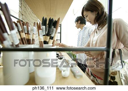 Young couple looking at items for sale on a shelf View Large Photo Image Stock Image - Young couple looking at items for sale on a shelf. Fotosearch
