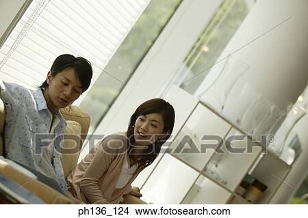 Young couple sitting together on a couch View Large Photo Image Picture - Young couple sitting together on a couch. Fotosearch