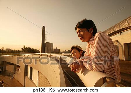 Young couple standing against a bridge railing View Large Photo Image Stock Photography - Young couple standing against a bridge railing. Fotosearch