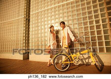 Young couple standing holding a bicycle View Large Photo Image Stock Image - Young couple standing holding a bicycle. Fotosearch
