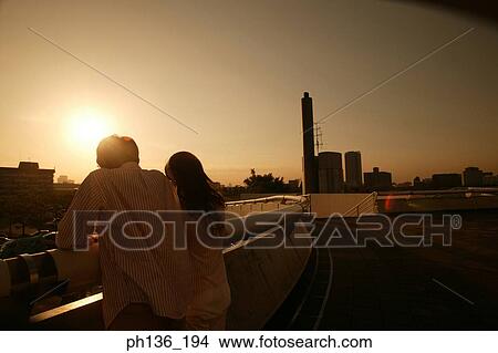 Picture - Young couple standing near a bridge railing. Fotosearch