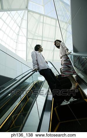 Stock Photo - Young couple standing on an escalator. Fotosearch