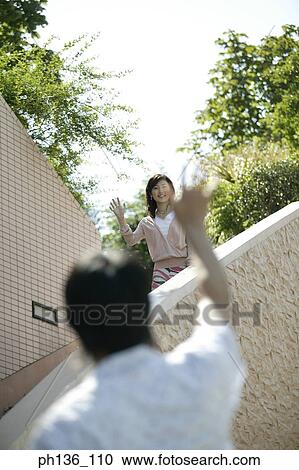 Stock Image - Young couple Waving at each other. Fotosearch