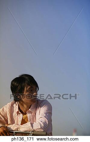 Stock Image - Young man sitting on a bicycle looking back. Fotosearch