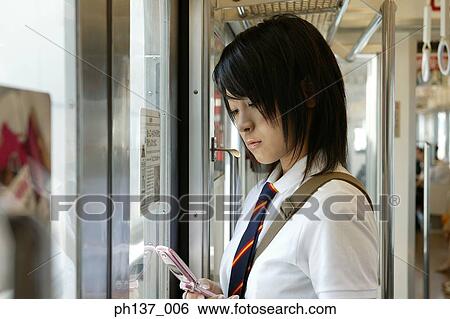 Teenage girl operating a mobile phone in a train View Large Photo Image Stock Photograph - Teenage girl operating a mobile phone in a train. Fotosearch