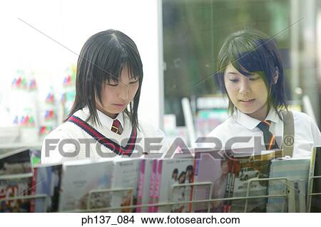 Picture - Teenage girls standing at a magazine rack. Fotosearch