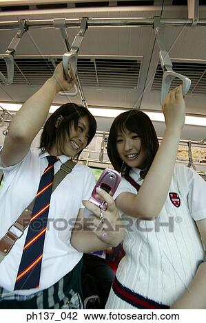 Teenage girls standing in a train operating mobile phone View Large Photo Image Stock Image - Teenage girls standing in a train operating mobile phone. Fotosearch