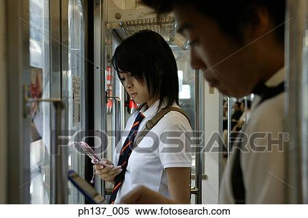 Teenagers in a train operating mobile phones View Large Photo Image Stock Photography - Teenagers in a train operating mobile phones. Fotosearch