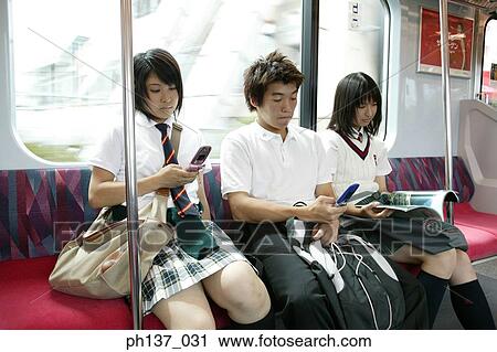 Teenagers sitting in a train operating mobile phones View Large Photo Image Stock Image - Teenagers sitting in a train operating mobile phones. Fotosearch