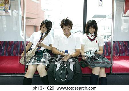Teenagers sitting in a train operating mobile phones View Large Photo Image Stock Photo - Teenagers sitting in a train operating mobile phones. Fotosearch