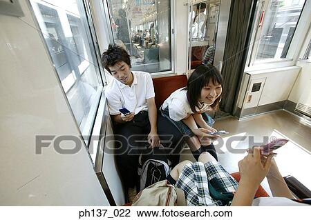 Stock Image - Teenagers sitting in a train talking. Fotosearch