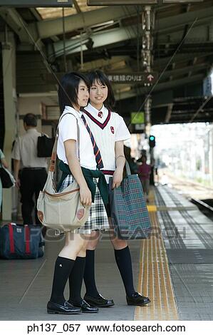 Stock Photo - Two teenage girls standing at a train station. Fotosearch