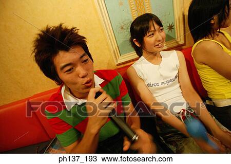 Stock Image - Teenagers singing at a karaoke bar. Fotosearch
